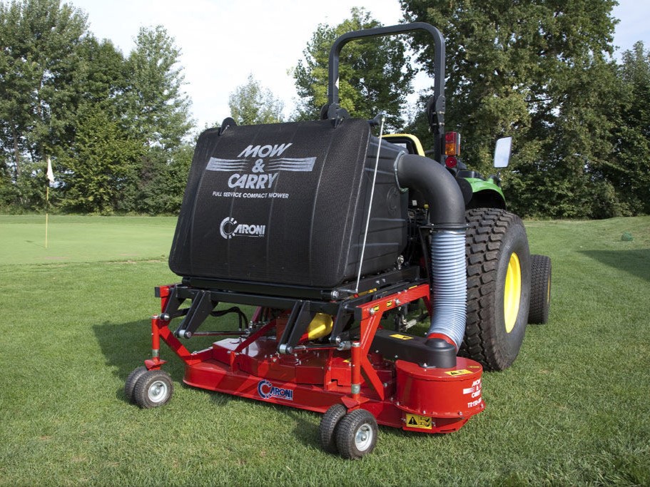 Red mower attachment hitched to a tractor on a grassy field, large black tank labeled 'Mow & Carry' strapped above the deck