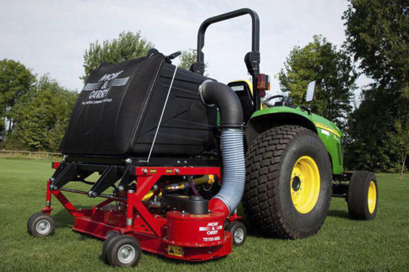Green tractor connected to a large red mowing attachment on a grassy field. (Informative)
