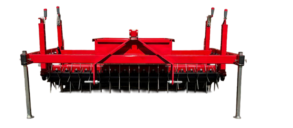 Red agricultural cultivator/harrow with many metal tines mounted on a frame against a brick wall, outdoor utility equipment.